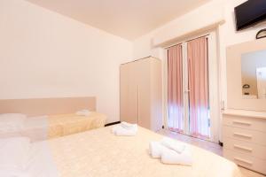 里米尼伽利略酒店的一间白色卧室,配有两张床和梳妆台