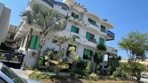 伊斯兰堡Midways Guest House and Hotels的一座白色的建筑,前面有棕榈树