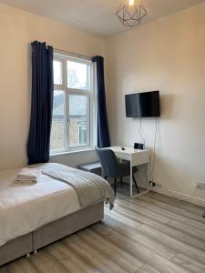 伦敦Camberwell Living Studio - Zone 2 London的一间卧室配有一张床、一张书桌和一个窗户。