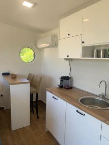 科托尔Glamping nature Tiny house的厨房配有白色橱柜、水槽和桌子