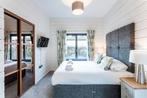 罗伊登Roydon Marina - Lodge 4 - Hot Tub的一间卧室配有一张大床和镜子