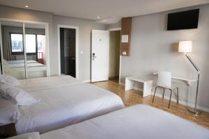 钱塔达莫伽依酒店的一间卧室配有两张床、一张桌子和一台电视。