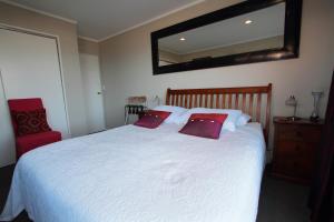 惠灵顿太平洋美景住宿加早餐旅馆的卧室配有白色床和2个红色枕头