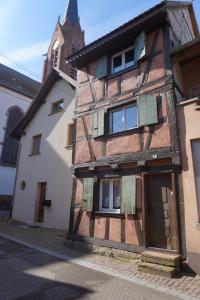 ScherwillerCoeur de village - maison de village - au centre - proche vignoble的一座古老的木结构建筑,后面有一座教堂