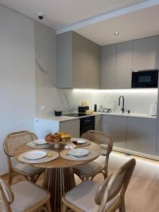 MoreiraOPORTO Suites的厨房配有带椅子的木桌和桌子。
