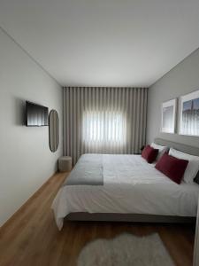MoreiraOPORTO Suites的卧室配有带红色枕头的大型白色床