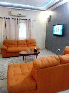 洛美EKA ELITE HOTEL的客厅配有2张橙色沙发和1张桌子