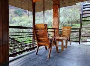 ShirirCrazy House Devku's Villa的门廊上设有两张木椅和一张桌子