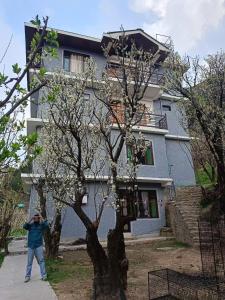 ShirirCrazy House Devku's Villa的站在房子前面的树旁的人