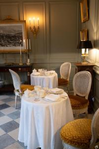 罗什科尔邦Manoir des Basses Rivières的一间用餐室,配有2张带白色桌布的桌子