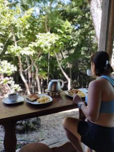 LepantoMágica cabaña en medio del bosque en Isla Venado的坐在餐桌上吃盘子的女人