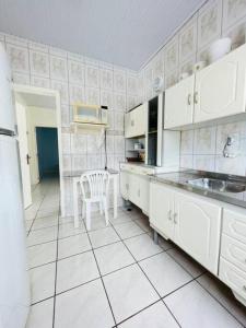 阿罗约多萨尔Casa de Praia Aconchegante e Próxima da Praia的厨房配有白色橱柜、桌子和椅子