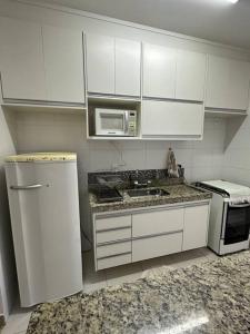 圣卡洛斯Apto Apólo - 3 dorm Wifi的厨房配有白色橱柜、水槽和微波炉