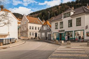 卑尔根Bryggen // Fløyen Apartments的一座空荡荡荡的街道,有建筑和山