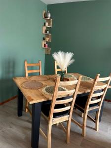 圣雅克德拉朗德CHARMANT APPARTEMENT AVEC GRANDE CAPACITÉ D’ACCUEIL的木制餐桌,配有四把椅子和绿色的墙壁