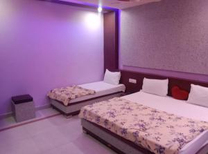 Sītāpur MūāfiHotel Parvati Residency的紫色墙壁客房的两张床