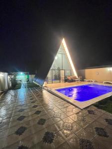 盖贝莱Gabala Twin A Frame Villas的大楼内的一个夜间游泳池,灯光照亮