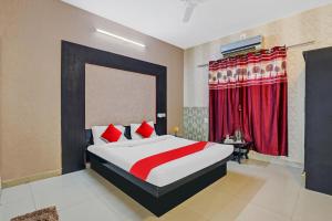 艾哈迈达巴德OYO Hotel Sargam的一间卧室配有一张带红色窗帘的大床
