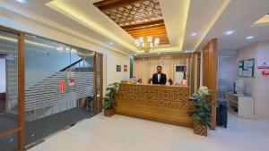 达卡Hotel Grand Circle Inn Dhaka的站在餐厅柜台的男人