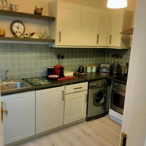 恩尼斯Russell Mews的厨房配有白色橱柜、水槽和洗碗机。