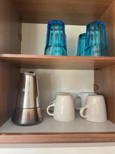 埃尔帕尔马Caravanas Con Encanto El Palmar的一个带蓝色玻璃杯和茶壶的架子