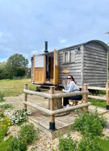 NewchurchUnder the Stars Shepherds Huts at Harbors Lake的坐在拖车前围栏上的女人