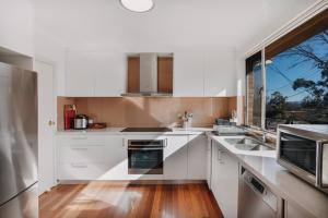 YarralumlaRestful Canberra Retreat in Spacious Terrace Home的厨房配有白色橱柜和窗户。