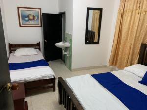 圣玛尔塔HOSTAL OLAS CLUB DE NEGUANJE -TAYRONA的一间卧室设有两张床、一个水槽和镜子