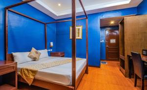 公主港Hotel Palacio Puerto Princesa的一间卧室配有一张蓝色墙壁的床