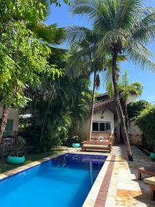 卡姆布库Kite Dream Cumbuco Apartments 60 & 120qm的棕榈树屋前的游泳池