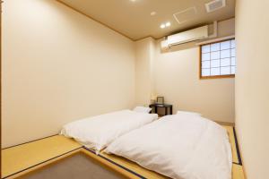 大阪Hostel OGK的带窗户的客房内的2张白色床