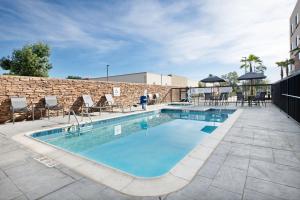 奇诺Fairfield by Marriott Inn & Suites Chino的一个带桌椅的游泳池以及砖墙