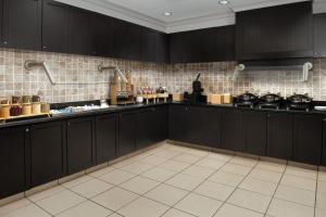 费耶特维尔Residence Inn by Marriott Fayetteville Cross Creek的厨房配有黑色橱柜和白色瓷砖地板。