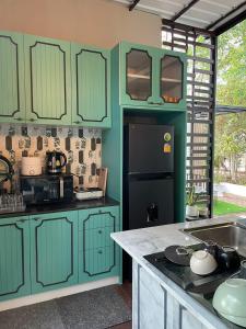 Thung Song356 Hostel的厨房配有绿色橱柜和黑色冰箱