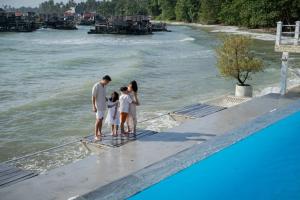 博拉科特Bintan Exotica Resort的站在水边的码头上的家庭