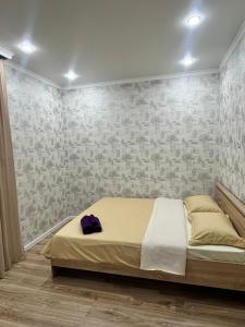 科克舍套Квартира посуточно的一间卧室,配有一张带紫色帽子的床