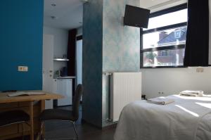 ReuverHet blauwe huis的客房设有床、书桌和窗户。
