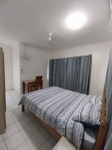 霍尼亚拉Harbour View House at Point Cruz, Honiara的一间卧室配有一张带窗帘和桌子的床