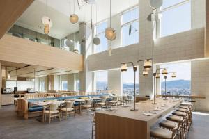 福井Courtyard by Marriott Fukui的餐厅设有桌椅和大窗户。