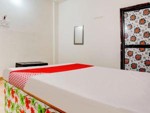 那格浦尔OYO Flagship RJ Hotel的卧室配有一张带红色毯子的白色床