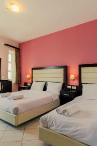 西洛卡特伦Hotel Kyani Akti的红色墙壁的酒店客房内的两张床