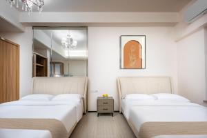 成都娅遇国际酒店公寓(新会展中心店)的白色墙壁客房的两张床