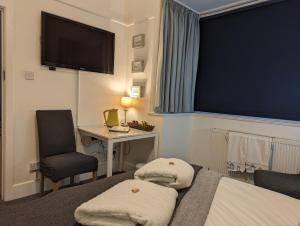 利明顿Cliftonville, en-suite room, fridge microwave TV, great value homestay near the sea的酒店客房配有一张床、一张书桌和一台电视。