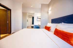 达累斯萨拉姆Urban by CityBlue, Dar es Salaam的卧室配有带橙色枕头的大型白色床