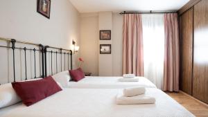 布里韦加埃利马公主酒店的一间卧室配有两张带白色床单和红色枕头的床。