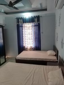 斋浦尔Comfort Inn Guesthouse的一间卧室设有两张床,窗户配有蓝色窗帘