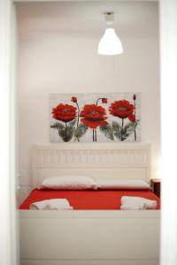 塔兰托蓝湾度假公寓的卧室配有一张挂着红色鲜花的床。