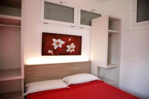 塔兰托蓝湾度假公寓的卧室配有红色的床,墙上挂有绘画作品