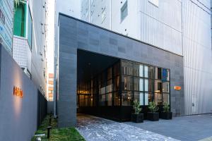 福冈HOTEL FORZA HAKATAEKI CHIKUSHIGUCHI Ⅱ的一座大型玻璃建筑,前面有盆栽植物