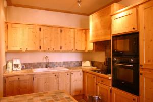 莱德萨阿尔卑斯Cortina - 12 - Appart confort - 8 pers的厨房配有木制橱柜和黑色用具